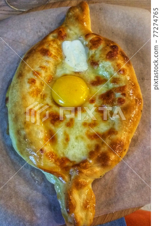 Khachapuri in Adjarian. Open pie with mozzarella and egg. Khachapuri in Adjarian. Open pie with mozzarella and egg. 77274765