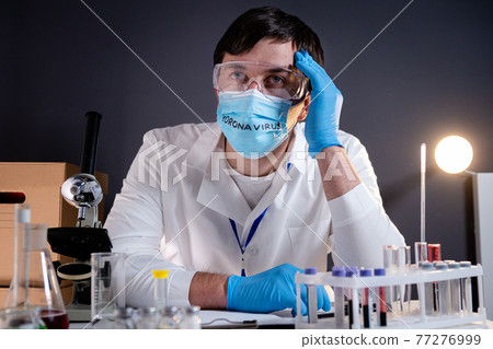 Tired, exhausted, devastated doctor scientist, after long shift, head in hands on face mask with text coronavirus. Lost hope concept, Covid-19 disease, global pandemic outbreak, SARS-CoV-2 Tired, exhausted, devastated doctor scientist, after long shift, head in hands on face mask with text coronavirus. Lost hope concept, Covid-19 disease, global pandemic outbreak, SARS-CoV-2 77276999