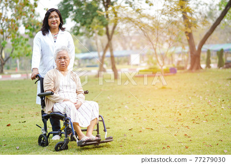 Doctor help and care Asian senior or elderly old lady woman patient sitting on wheelchair at nursing hospital ward 77279030