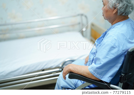 Asian senior or elderly old lady woman patient sitting on  wheelchair with bed at nursing hospital ward 77279115