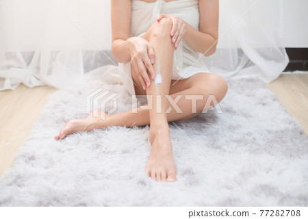 Woman applying natural cream, Woman moisturizing her leg with cosmetic cream with copy space. 77282708