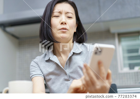 一個女人拿著智能手機，表情疲憊 77283374