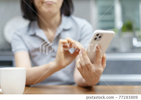 A woman looking at a smartphone with a stressed expression A woman looking at a smartphone with a stressed expression 77283809