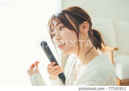 使用頭髮鐵的一個少婦 77285912