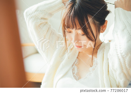 Young woman tying her hair together 77286017