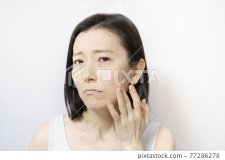 Middle-aged woman suffering from skin problems 77286278