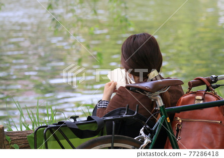 一個女人在池塘邊度假看書 一個女人在池塘邊度假看書 77286418