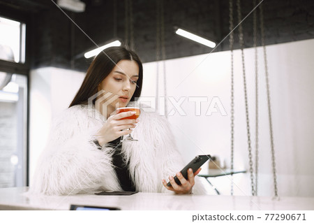 Girl drinking a red cocktail in a cafe Girl drinking a red cocktail in a cafe 77290671