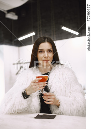 Girl drinking a red cocktail in a cafe 77290677