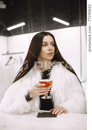 Girl drinking a red cocktail in a cafe Girl drinking a red cocktail in a cafe 77290682