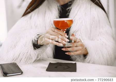 Girl drinking a red cocktail in a cafe 77290683
