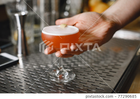 Red cocktail in a glass on a barstique 77290685