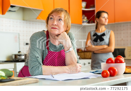Quarrel of an elderly mother and adult daughter in the kitchen 77292175