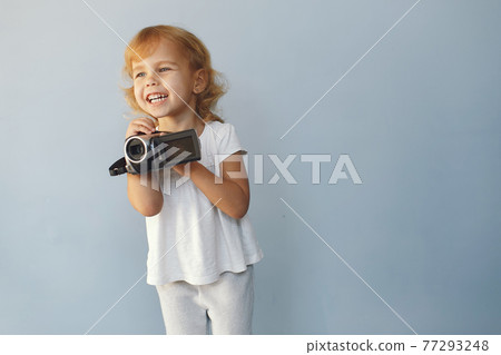 Cute little girl sitting in a studio on a blue background Cute little girl sitting in a studio on a blue background 77293248