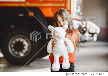 Girl near fire truck with a toy in hand Girl near fire truck with a toy in hand 77293298