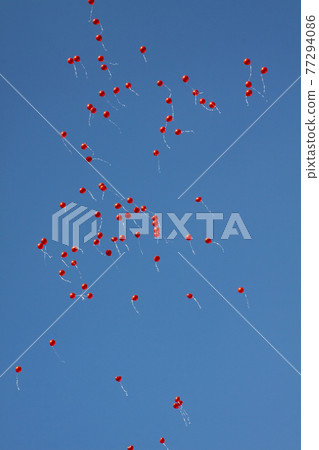 red balloons flying against the blue sky 77294086