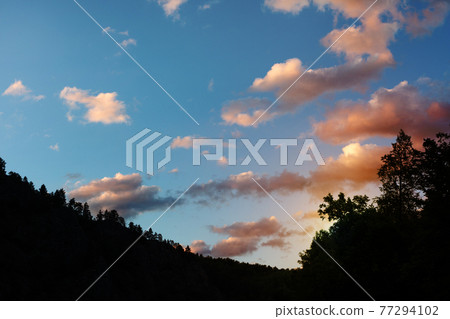 silhouette image of mountain. white clouds in the sunset sky on a background. sunset in the mountains 77294102