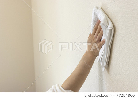 Women's hands wiping the walls with a towel 77294860