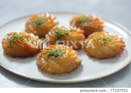 Turkish and Arabic Traditional Ramadan Dessert Lor Cheese Dessert with pistachio powder and syrup serving on plate. 77297505