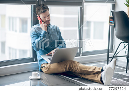 Dark-haired man working in the office and looking busy Dark-haired man working in the office and looking busy 77297524