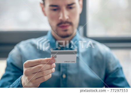 Young man in denim shirt making periodic payments online 77297553
