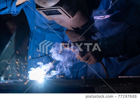Skillful metal worker working with arc welding machine in factory Skillful metal worker working with arc welding machine in factory 77297688