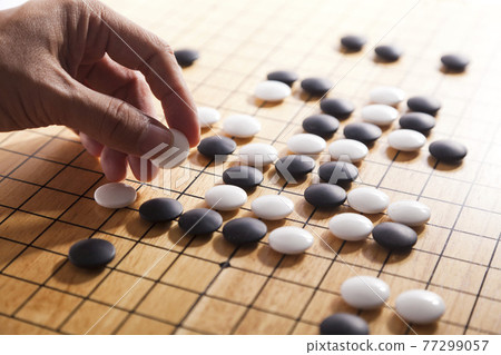 player's hand put stone on the game board - an ancient game also known as baduk in Korean, weiqi in Chinese and Igo in Japanese player's hand put stone on the game board - an ancient game also known as baduk in Korean, weiqi in Chinese and Igo in Japanese 77299057