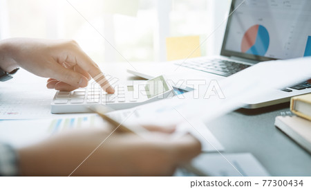Close up Businessman and partner using calculator and laptop for calculating finance, tax, accounting, statistics and analytic research concept Close up Businessman and partner using calculator and laptop for calculating finance, tax, accounting, statistics and analytic research concept 77300434