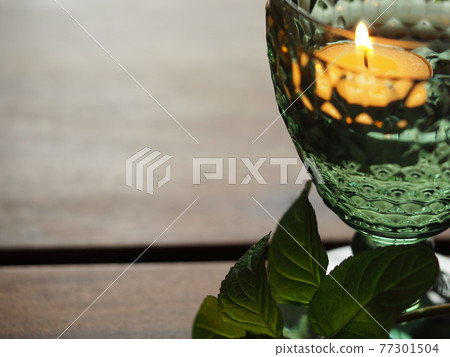Candles and mint branches floating in a green glass 77301504