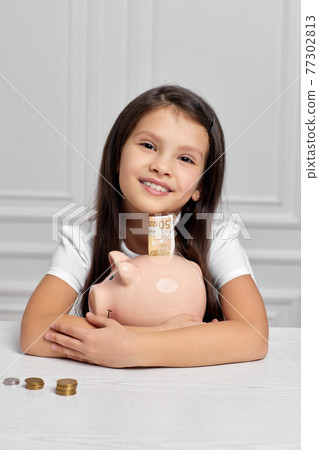 Little child girl with piggy bank at home Little child girl with piggy bank at home 77302813