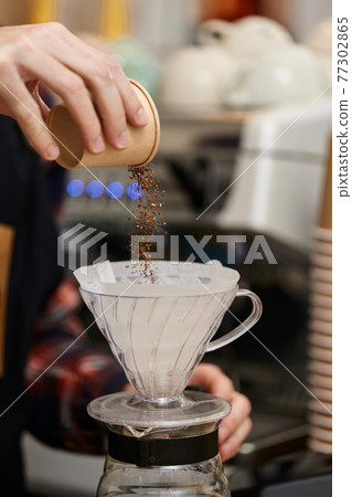 male hands pouring grounded coffee in filter. 77302865