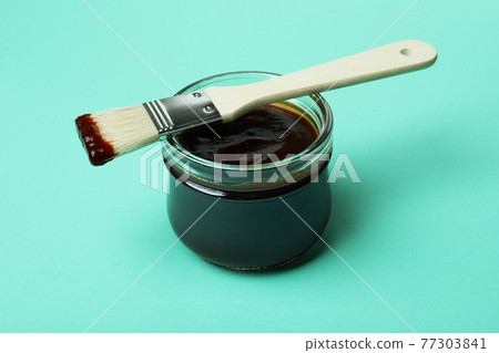 Glass jar of barbecue sauce and brush on mint background Glass jar of barbecue sauce and brush on mint background 77303841