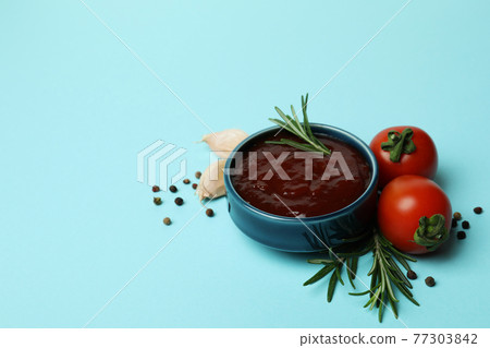 Bowl of barbecue sauce and spices on blue background Bowl of barbecue sauce and spices on blue background 77303842