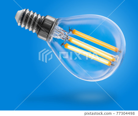 Energy efficient led filament Light Bulb Glowing isolated on blue background. 77304498