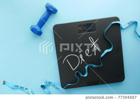 diet text on weight scale with dumbbell and measurement tape on blue diet text on weight scale with dumbbell and measurement tape on blue 77304887