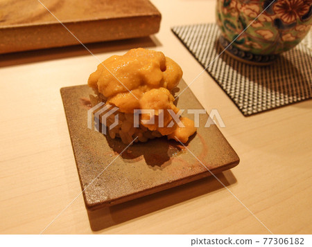 A piece of sea urchin (uni) sushi on a beautiful pottery at a high class sushi restaurant in Ginza, Tokyo, Japan. 77306182