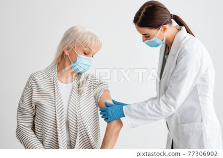 Senior Woman Receiving Coronavirus Vaccine Intramuscular Injection 77306902