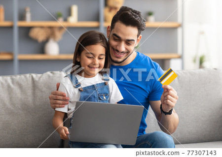 Family using computer and credit card at home Family using computer and credit card at home 77307143
