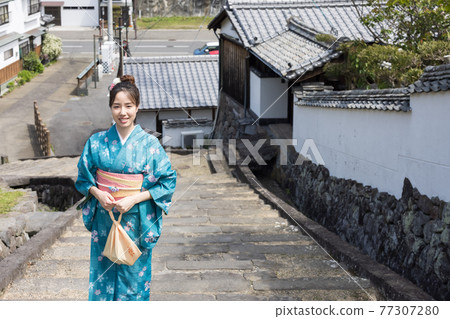 A young woman in a kimono taking a commemorative photo on the slope of Ameya [Kitsuki City] 77307280