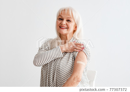 Smiling Mature Woman Showing Vaccinated Arm After Antiviral Injection Smiling Mature Woman Showing Vaccinated Arm After Antiviral Injection 77307372