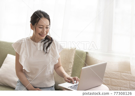 A woman operating a computer while sitting at home A woman operating a computer while sitting at home 77308126