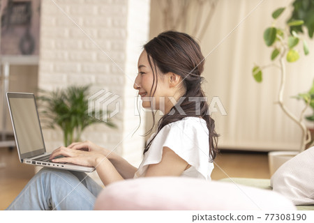 A woman operating a computer while sitting at home A woman operating a computer while sitting at home 77308190