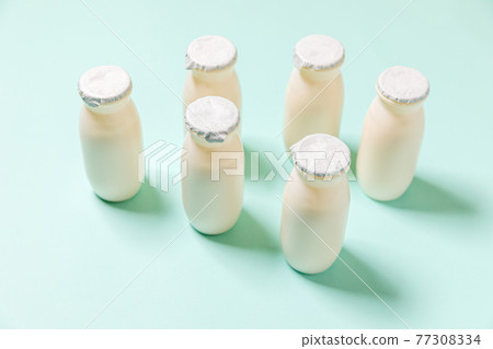 Small bottles with probiotics and prebiotics dairy drink on blue background. Production with biologically active additives. Fermentation and diet healthy food. Bio yogurt with useful microorganisms. Small bottles with probiotics and prebiotics dairy drink on blue background. Production with biologically active additives. Fermentation and diet healthy food. Bio yogurt with useful microorganisms. 77308334