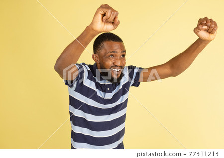 One African young man posing isolated over yellow studio background with copyspace for ad One African young man posing isolated over yellow studio background with copyspace for ad 77311213