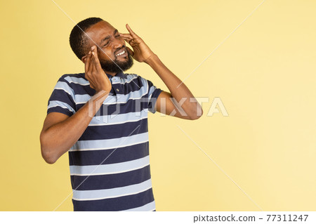 One African young man posing isolated over yellow studio background with copyspace for ad One African young man posing isolated over yellow studio background with copyspace for ad 77311247