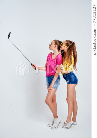 portrait of happy teenagers taking selfie together isolated on whitePortrait of happy teenagers in summer clothes, sunglasses taking selfie together isolated on white. 77312127