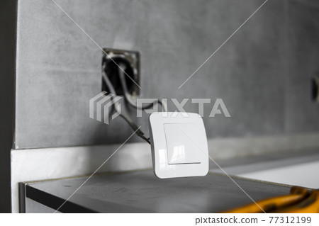 Repair or installation of a new light switch in the wall. Light switch connected via cables to a electricity in a home. 77312199
