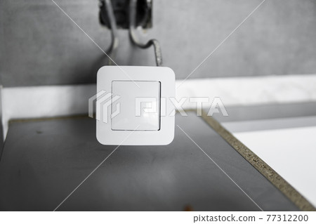 Repair or installation of a new light switch in the wall. Light switch connected via cables to a electricity in a home. 77312200