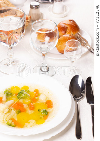 Plate with fresh hot soup on the table and homemade buns Plate with fresh hot soup on the table and homemade buns 77312546