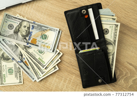Laptop and wallet with credit card and cash money on a wooden desktop, online payment systems and banking concept. 77312754